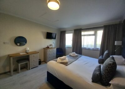 A family room with dressing table, TV and chest of drawers.