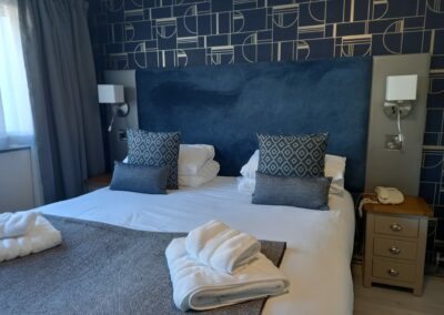 A double room with large headboard in blues and greys.