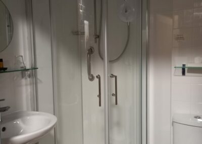 A walk in shower with basin and mirror